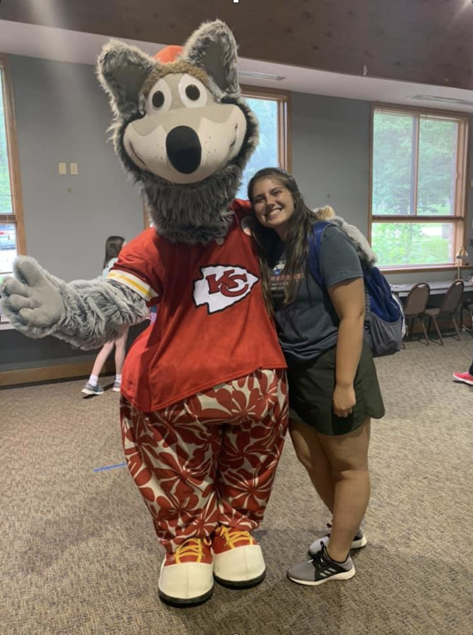 Girl standing with an animal mascot wearing a Kansas City Chiefs shirt