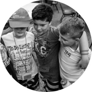 Black and white photo of boys at camp with their arms around each other's shoulders